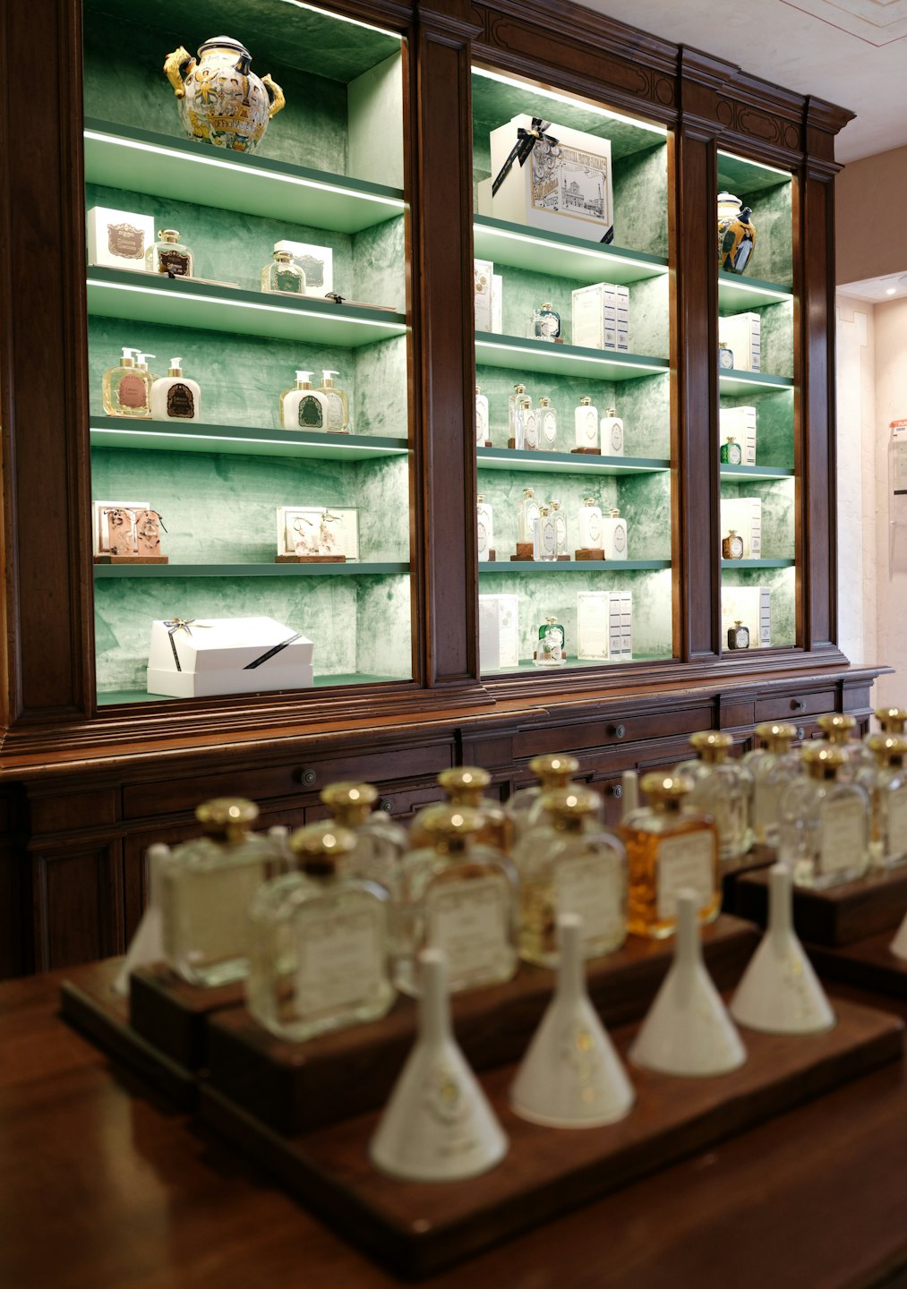 Profumi e cosmetici di lusso esposti su scaffali foderati di velluto.
