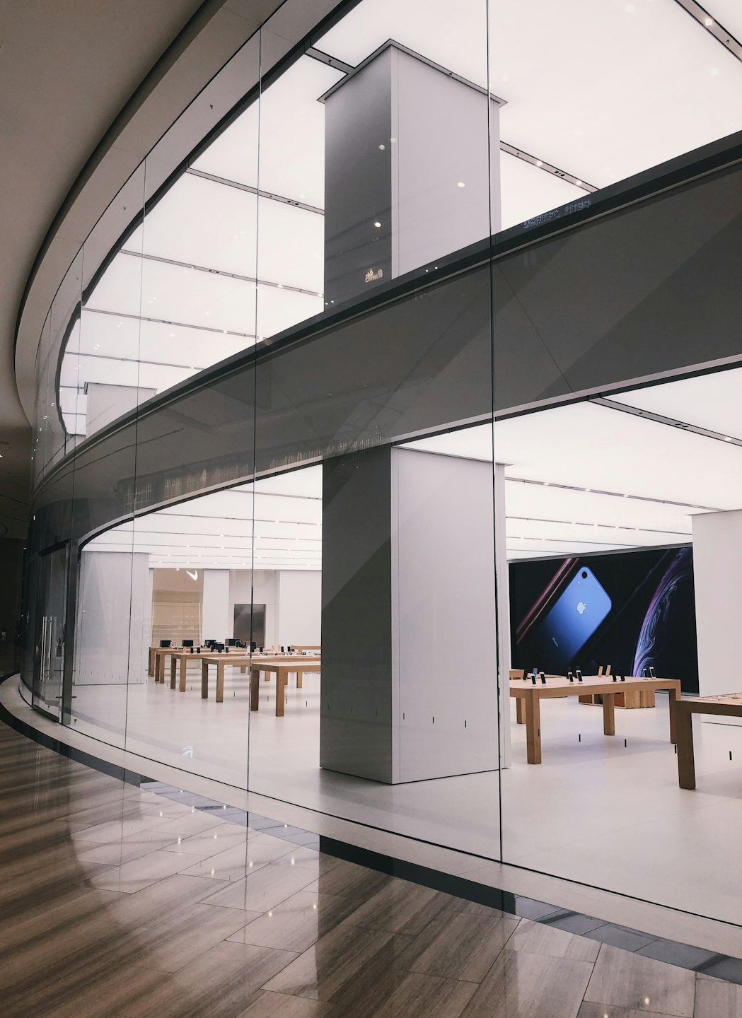 Dispositivi elettronici esposti su tavoli di legno all'interno di un negozio moderno.